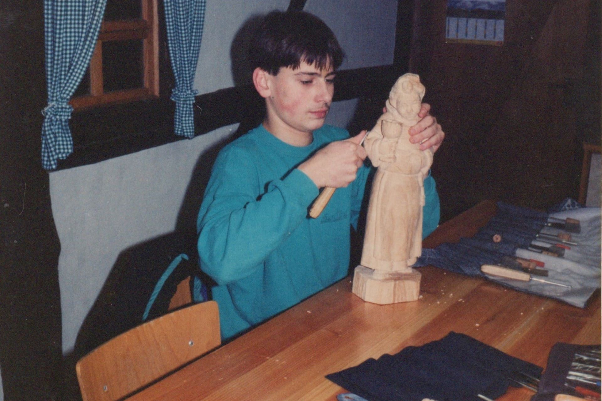 Person sitzt und schnitzt an einer Figur